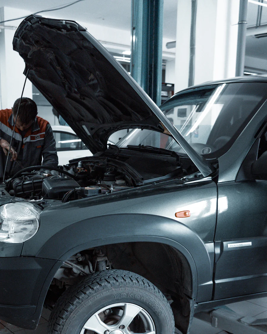 A mechanic working on an SUV with its hood open in a bright repair shop