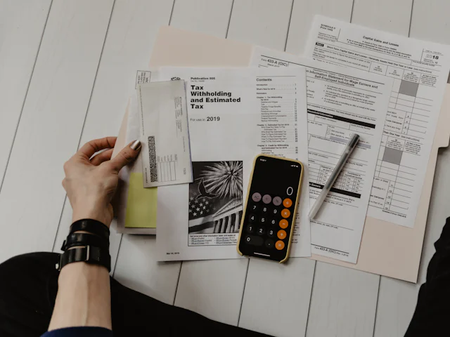 Tax forms, a pen and a phone calculator on a desk